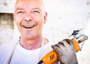 Man Holding Drill and Smiling